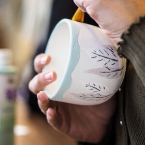 Eine Tasse aus Keramik beim Bemalen mit Pinsel